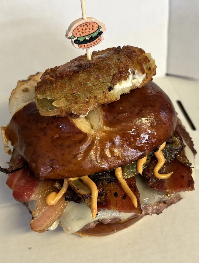 The Centennial Burger with a jalapeño popper on a pretzel bun